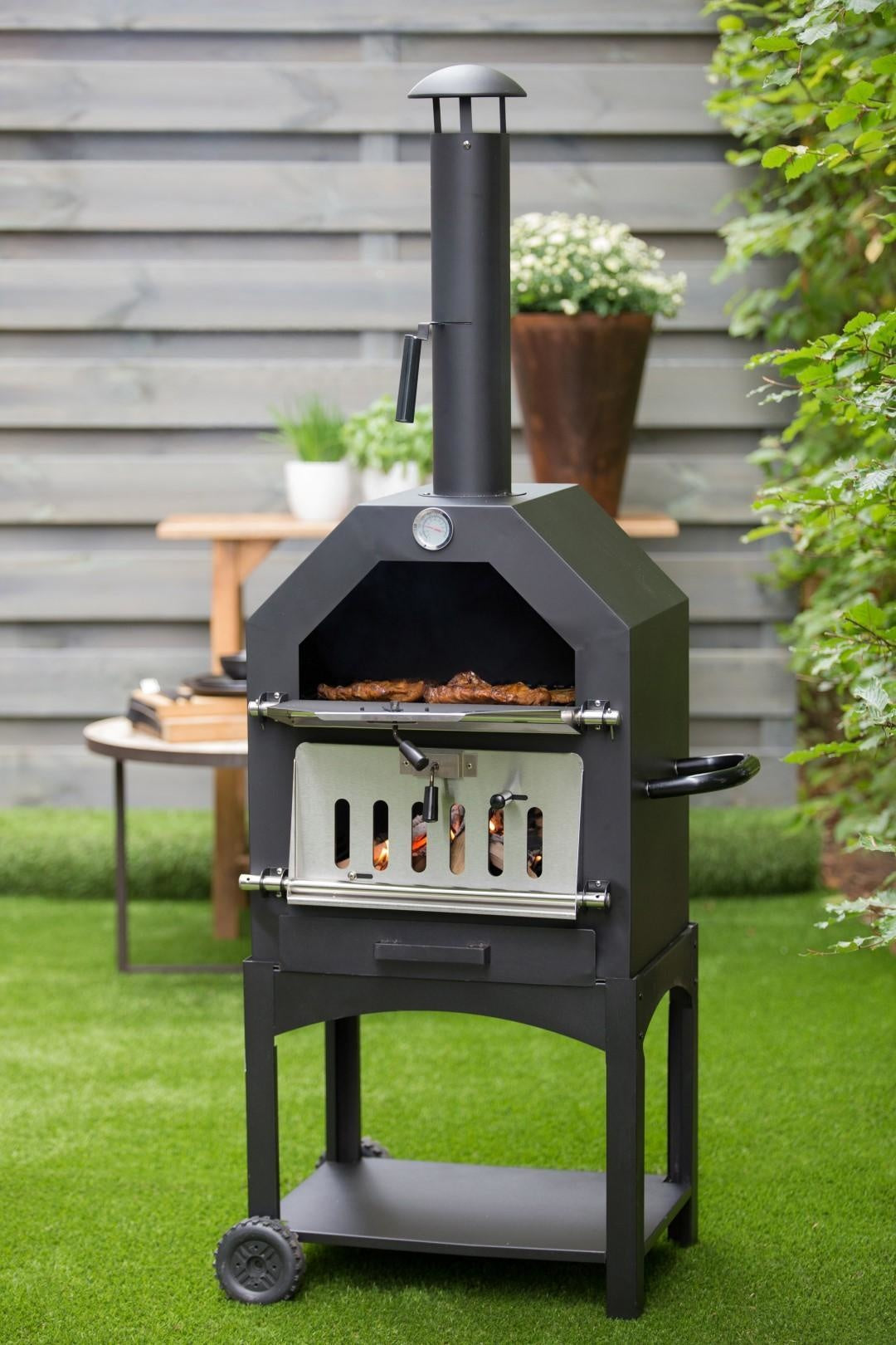 Donkere buiten-pizzaoven met open ovenmond en gereedschap aan de frontzijde