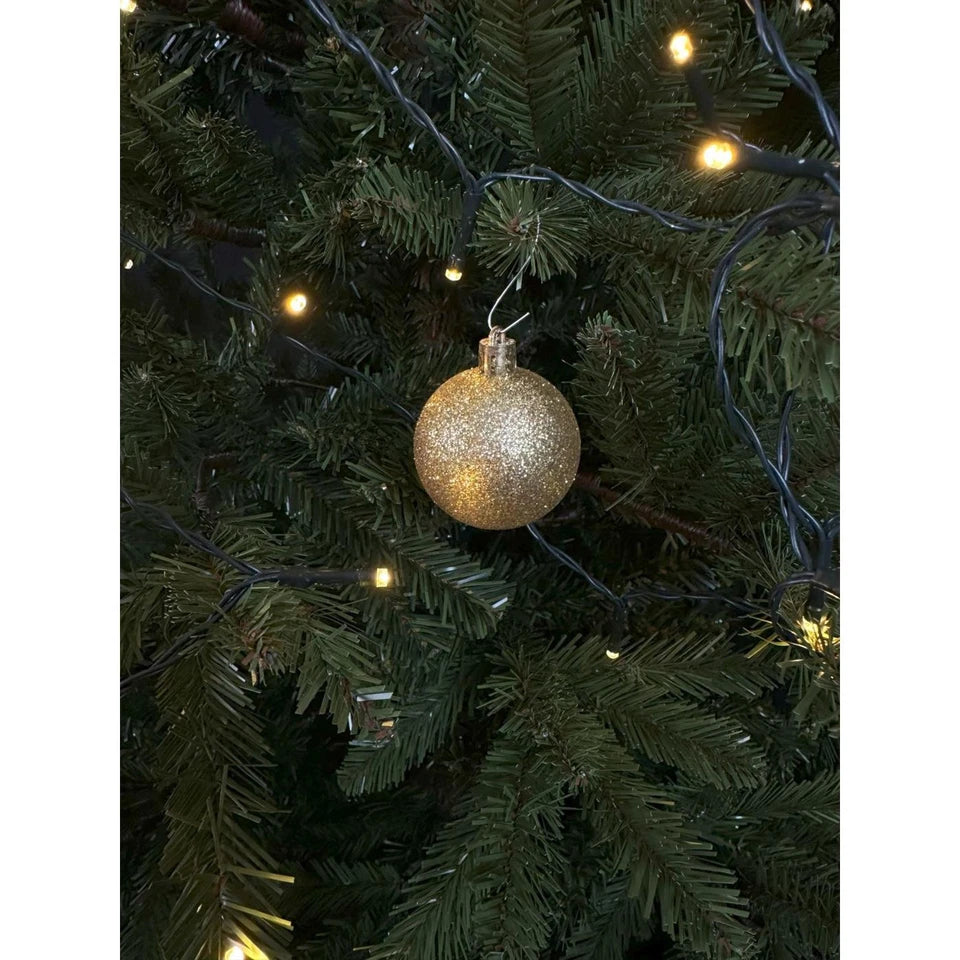 Goudkleurige kunststof kerstbal met glitteroppervlak en ophanghaak op kerstboom