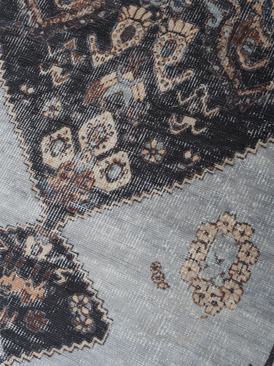 Vloerkleed detail met ingeweven patroon in antraciet, bruin en lichtgrijze tinten