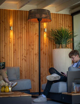 Staande terrasverwarmer met geperforeerde ronde kap en brandend verwarmingselement.