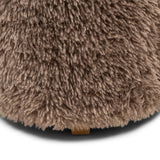 Detail van de pluizige bekleding en het houten voetje van de taupe poef