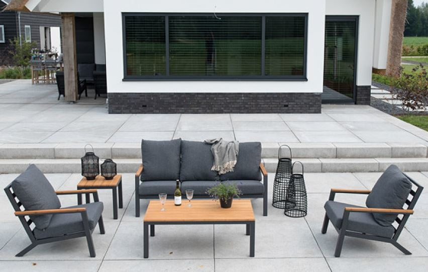 Loungeset op terras met grijze bank en fauteuils, houtlook salontafel en zwarte frames