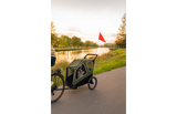 Groene fietskar op pad met opklapbare rode vlag en doorzichtige zijpanelen
