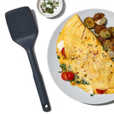 OXO siliconen spatel naast bord met gerecht, donkergrijs