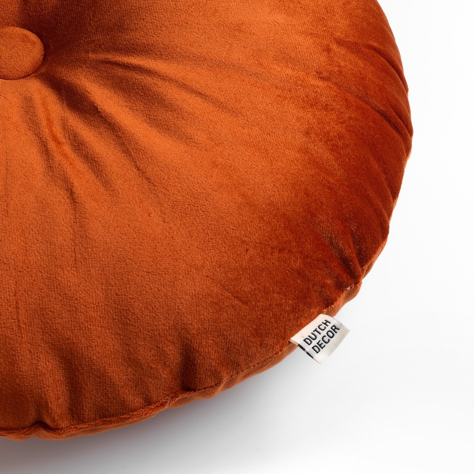 Rond roestoranje sierkussen, close-up label en plooien op veloursstof.