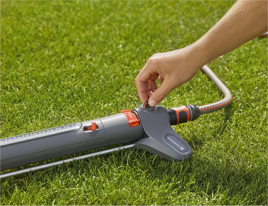 Gardena zwenksproeier met rood-blauwe knoppen, aangesloten op slang