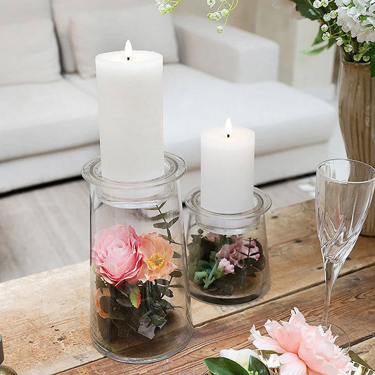 Witte LED-stompkaarsen op glazen potten op een houten tafel