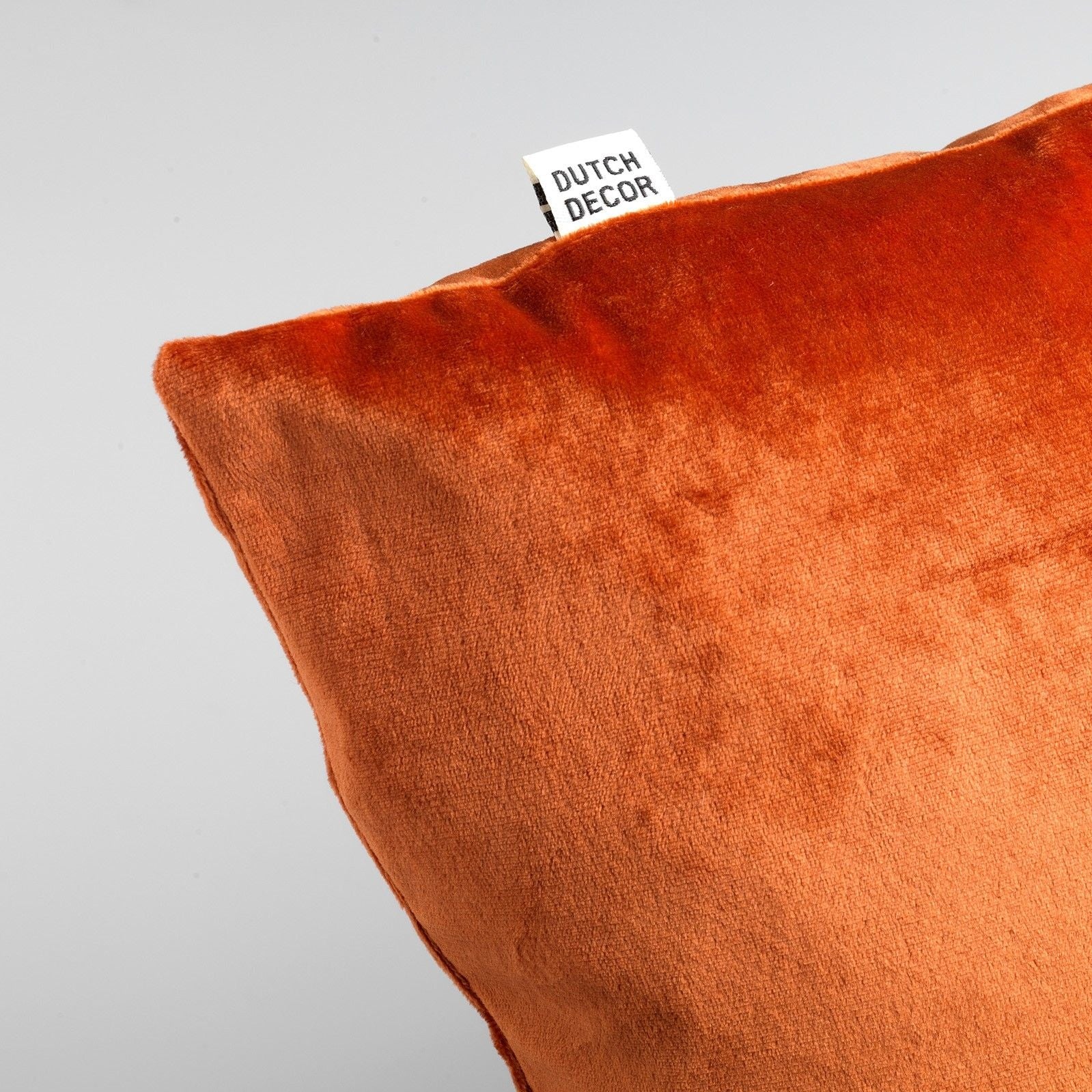 Terracotta sierkussen-hoes met schuin zicht en klein label bij de rand