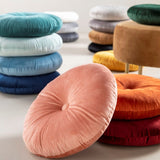 Rond roze sierkussen met knoopdetail van veloursstof.