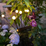 Zonne-energie priklamp met meerdere brandende lampjes tussen bladeren en bloemen
