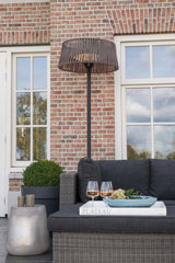 Staande terrasverwarmer met ronde kap naast buitentrampoline en donkergrijze bank.