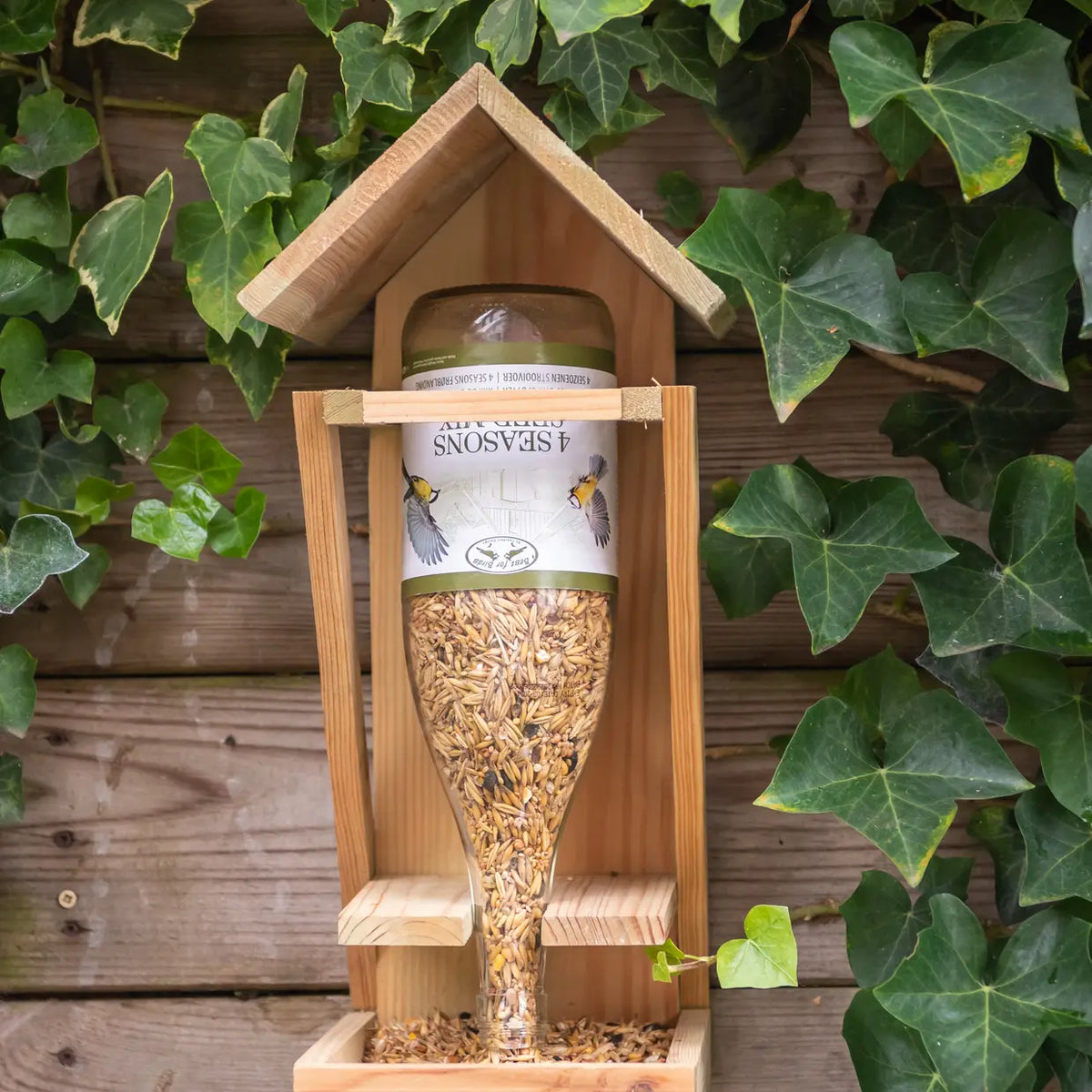 Houten wijnflesvoedertafel met glazen fles en vogelzaad in houten nesthuis