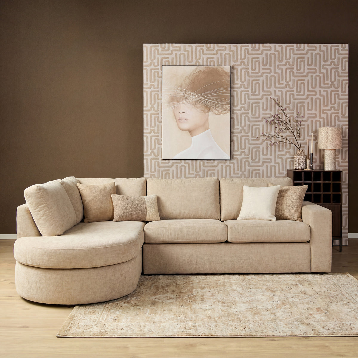 Lichtroze hoekbank met chaise en meerdere kussens, ronde zit en zachte textielbekleding