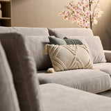 Beige zitgedeelte met decoratief sierkussen en gestikt patroon in textiel.