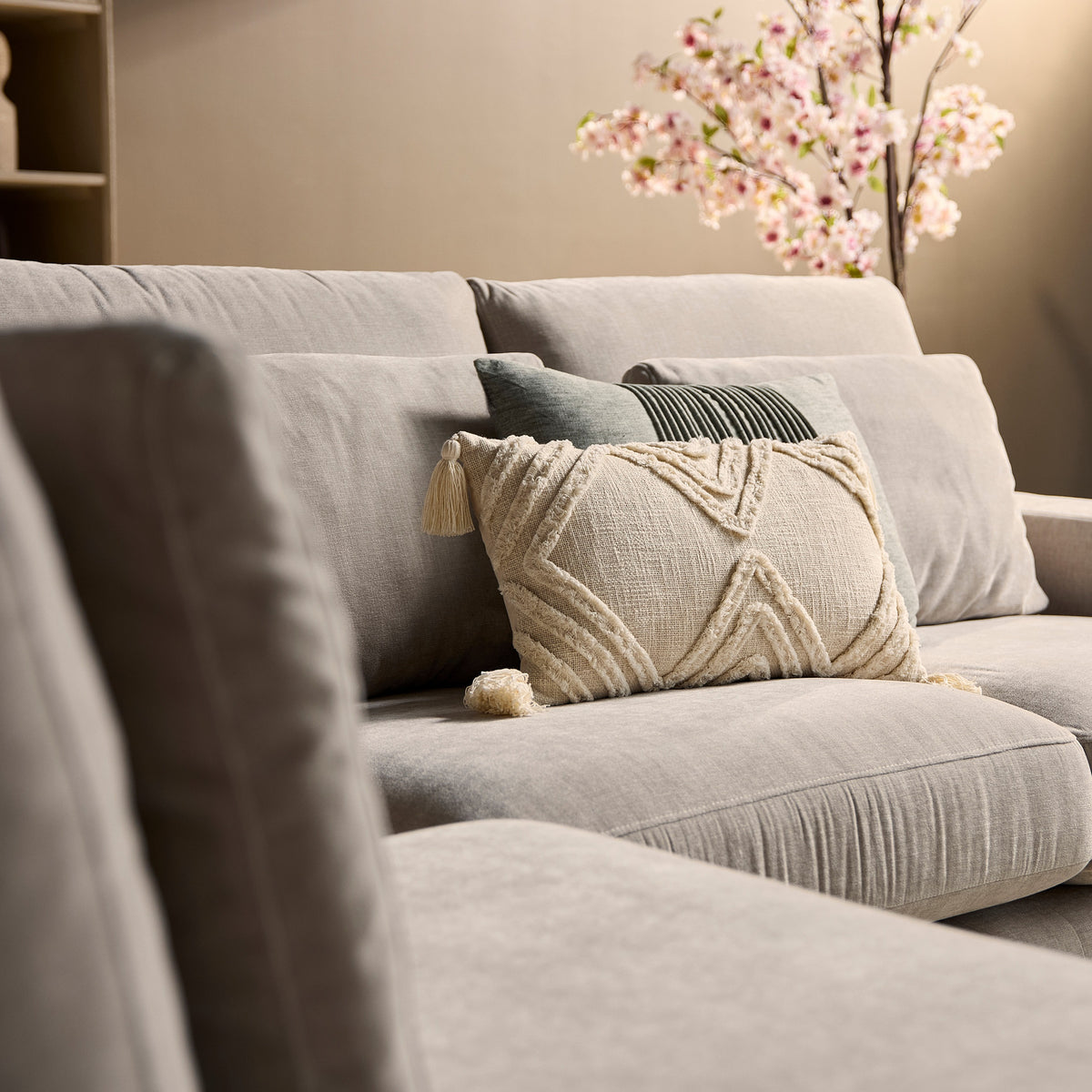 Beige zitgedeelte met decoratief sierkussen en gestikt patroon in textiel.
