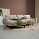 Lichtbeige hoekbank met chaise longue links en groene plaid op de chaise
