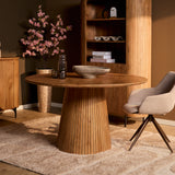 Ronde eettafel met naturel houten blad op centrale ribbelsokkel, met eetstoelen
