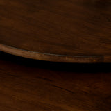 Donkerbruine houten bladrand van een ronde salontafel met zwarte metalen frame