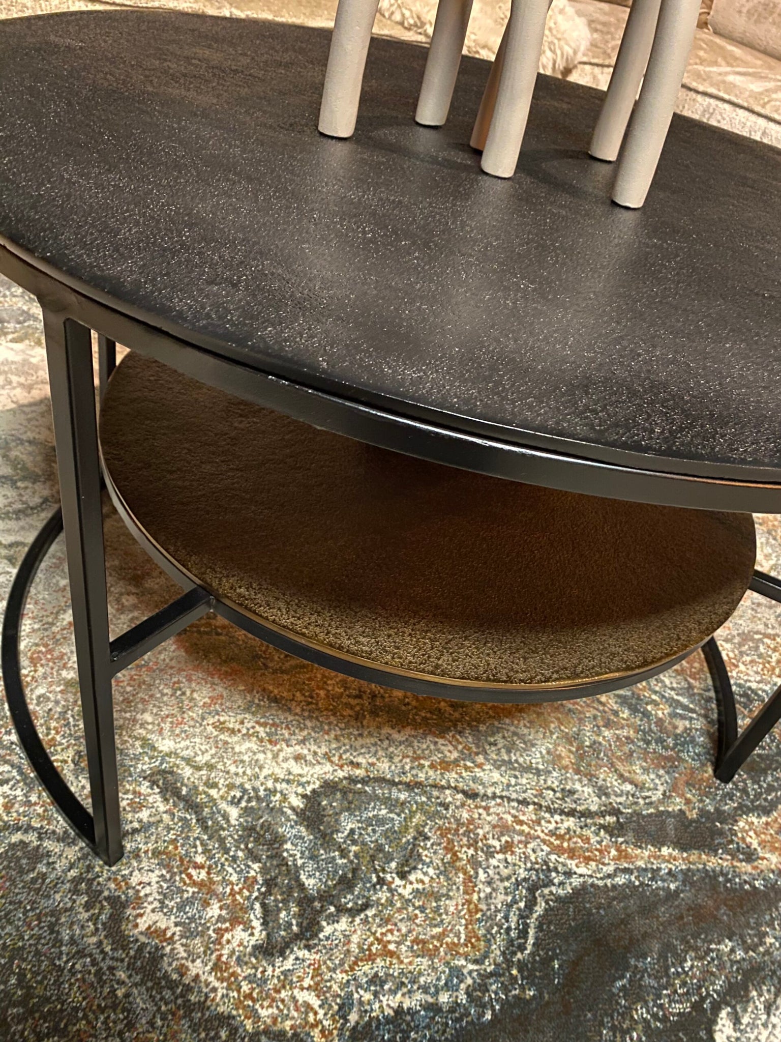 Zwarte salontafel met afgerond blad en metalen frame, ronde onderplank onder tafel