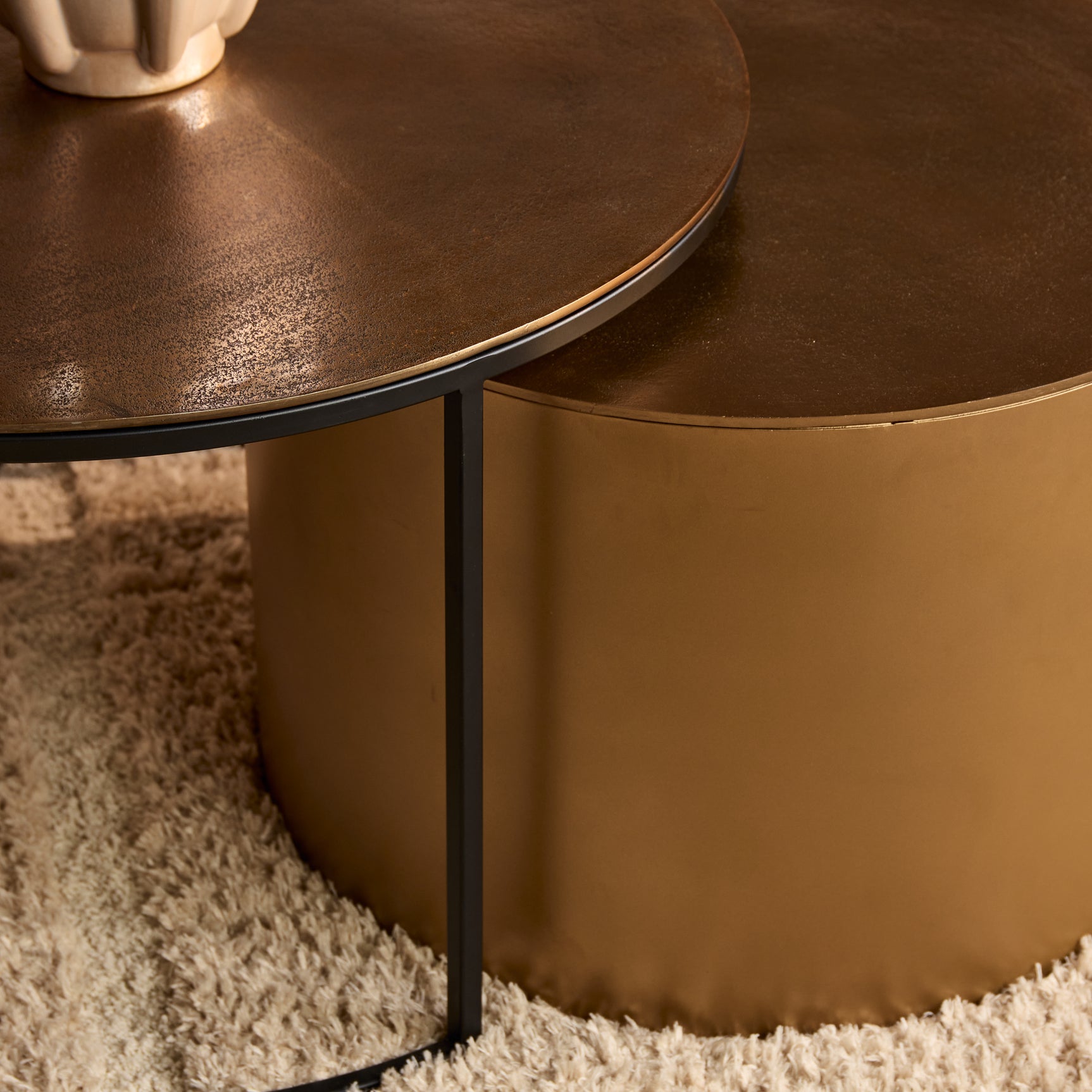 Ronde salontafel met goudkleurige zijkant en donkere metalen poten, blad met rand