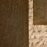 Hoekdetail van goudbruine salontafel met glanzende metalen rand en textuur