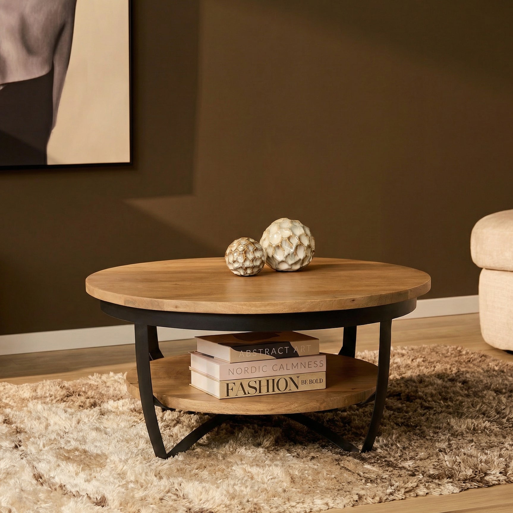 Ronde salontafel met licht mangohouten blad en zwart metalen frame, plank eronder