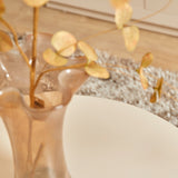 Witte salontafel met rond blad en vaas met bladeren en vlinders