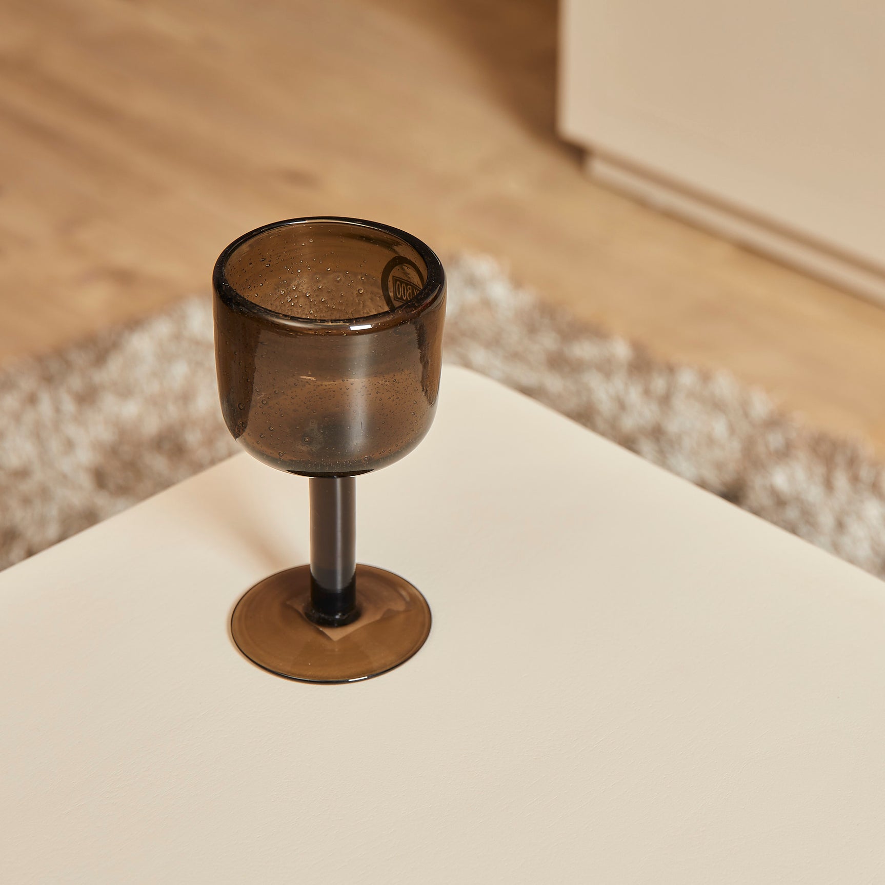 Salontafel Saya met roomwit tafelblad en kaarsglas op het oppervlak