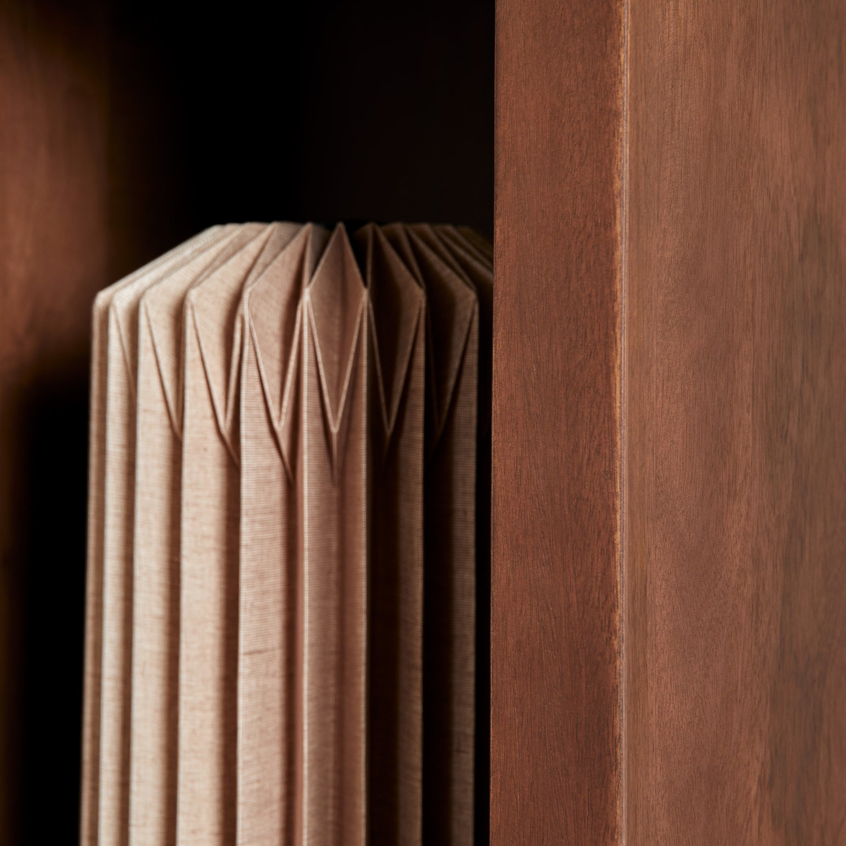 Opbergvak met opgevouwen beige textiel en houten zijwand