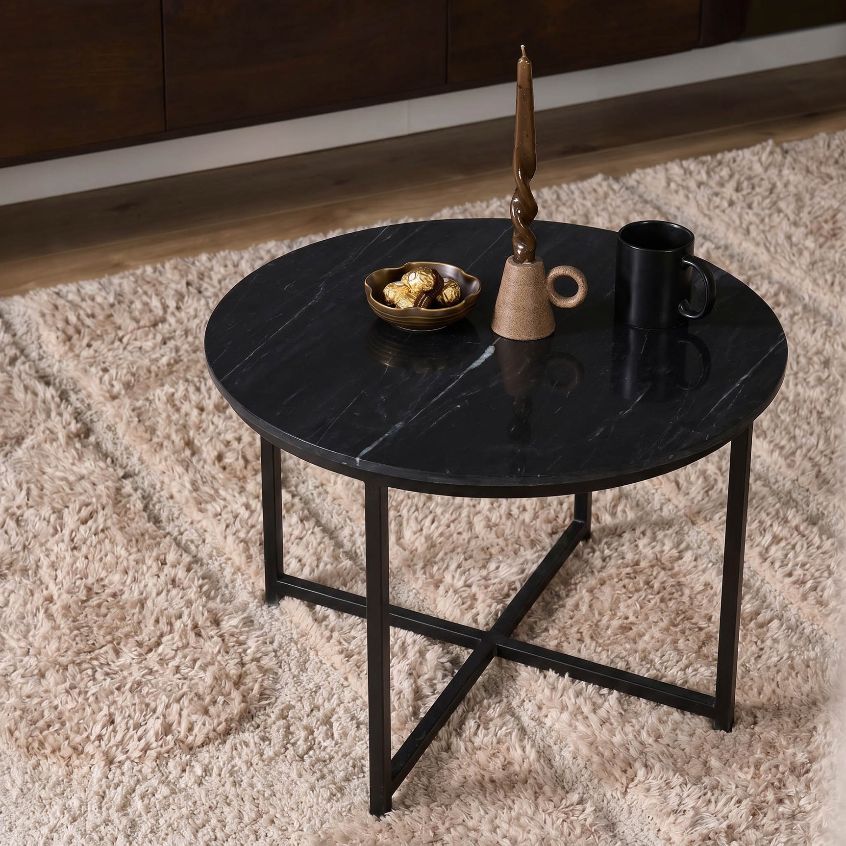 Ronde salontafel met zwart gemarmerd blad en zwart metalen poten, decor op het blad.