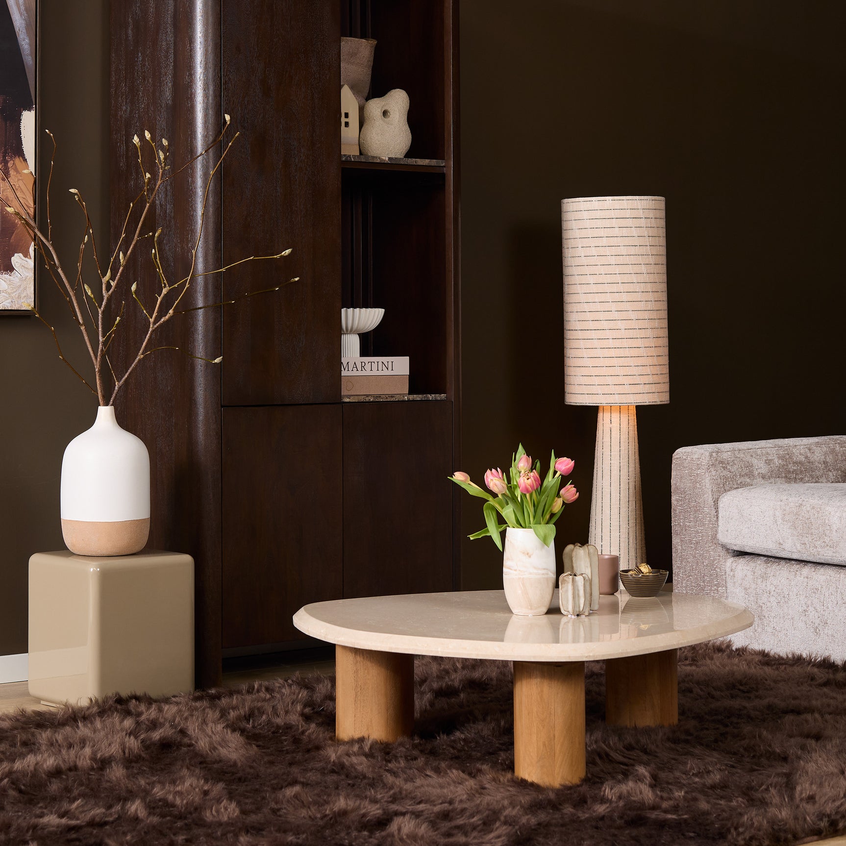 Ronde salontafel met licht marmeren blad, houten poot, met vaasje en lamp ernaast