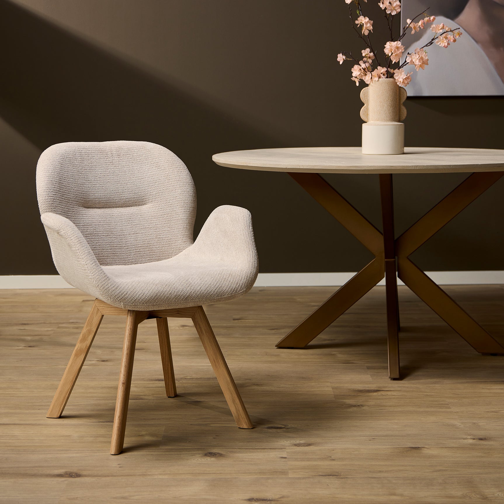 Beige eetkamerstoel met houten poten, ronde kuip en brede armleuningen