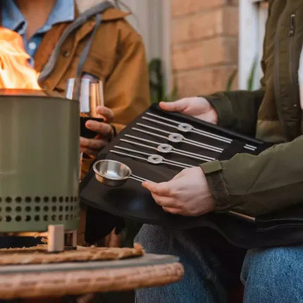 Solo Stove Mesa accessoireset in gebruik: metalen schepje en stokken vastgehouden