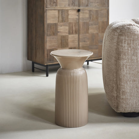 Zandkleurige Cascais bijzettafel van Rivièra Maison met geribbelde voet naast een fauteuil