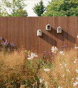 Beige vogelhuisje(s) aan houten schutting met ronde ingangen