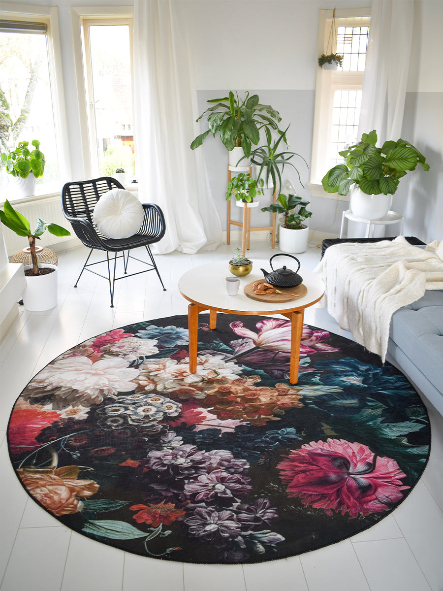 Rond vloerkleed met grote bloemen in roze, blauw en wit op donkere basis