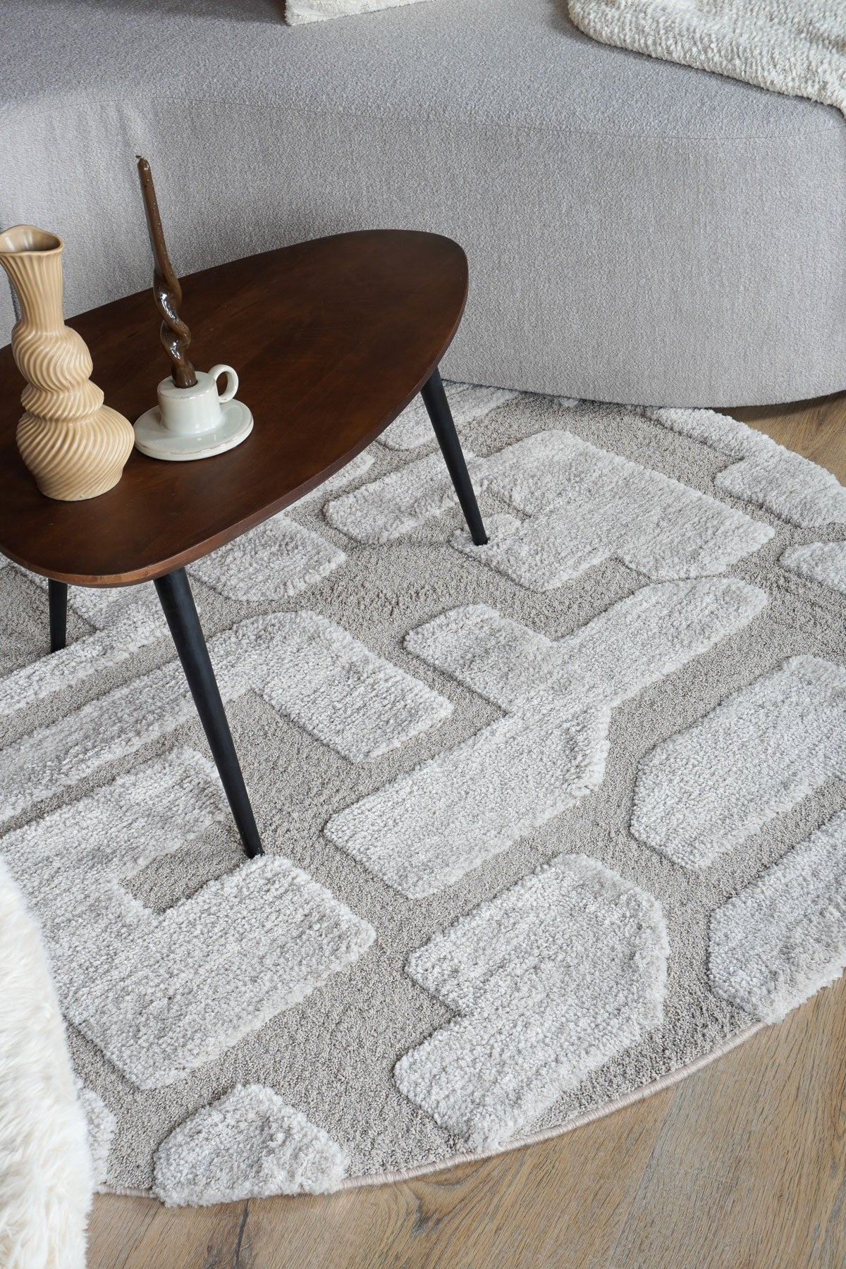 Rond vloerkleed met grijs-beige ingelegd patroon en korte, zachte pool.