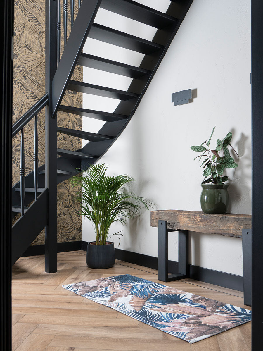Vloerkleed met tropisch bladmotief in blauw en beige, op houten vloer