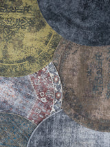 Rond vloerkleed in grijsblauwe tint met decoratief oosters patroon, zichtbaar deel