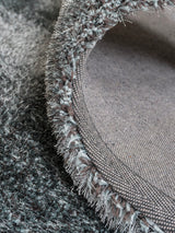 Rond vloerkleed-detail met blauwgrijze franjerand en geweven bies aan de rand