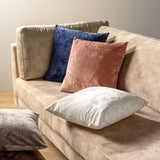 Set sierkussens op beige bank, waaronder blauw fluweel in vierkante vorm
