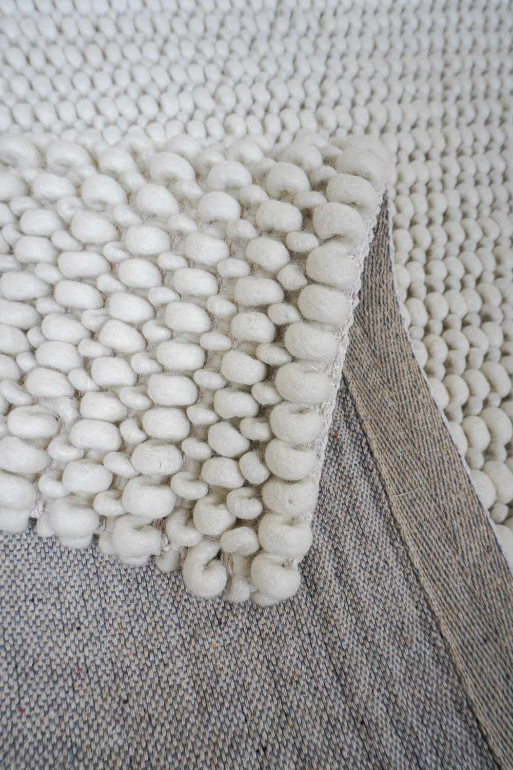 Wit vloerkleed met dikke lussen en afgewerkte rand, close-up