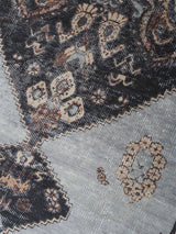 Vloerkleed detail met ingeweven patroon in antraciet, bruin en lichtgrijze tinten