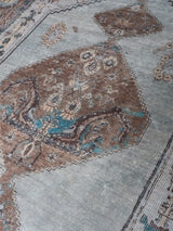 Vloerkleed close-up met grijsblauwe basis en bruinblauwe medaillons en randen
