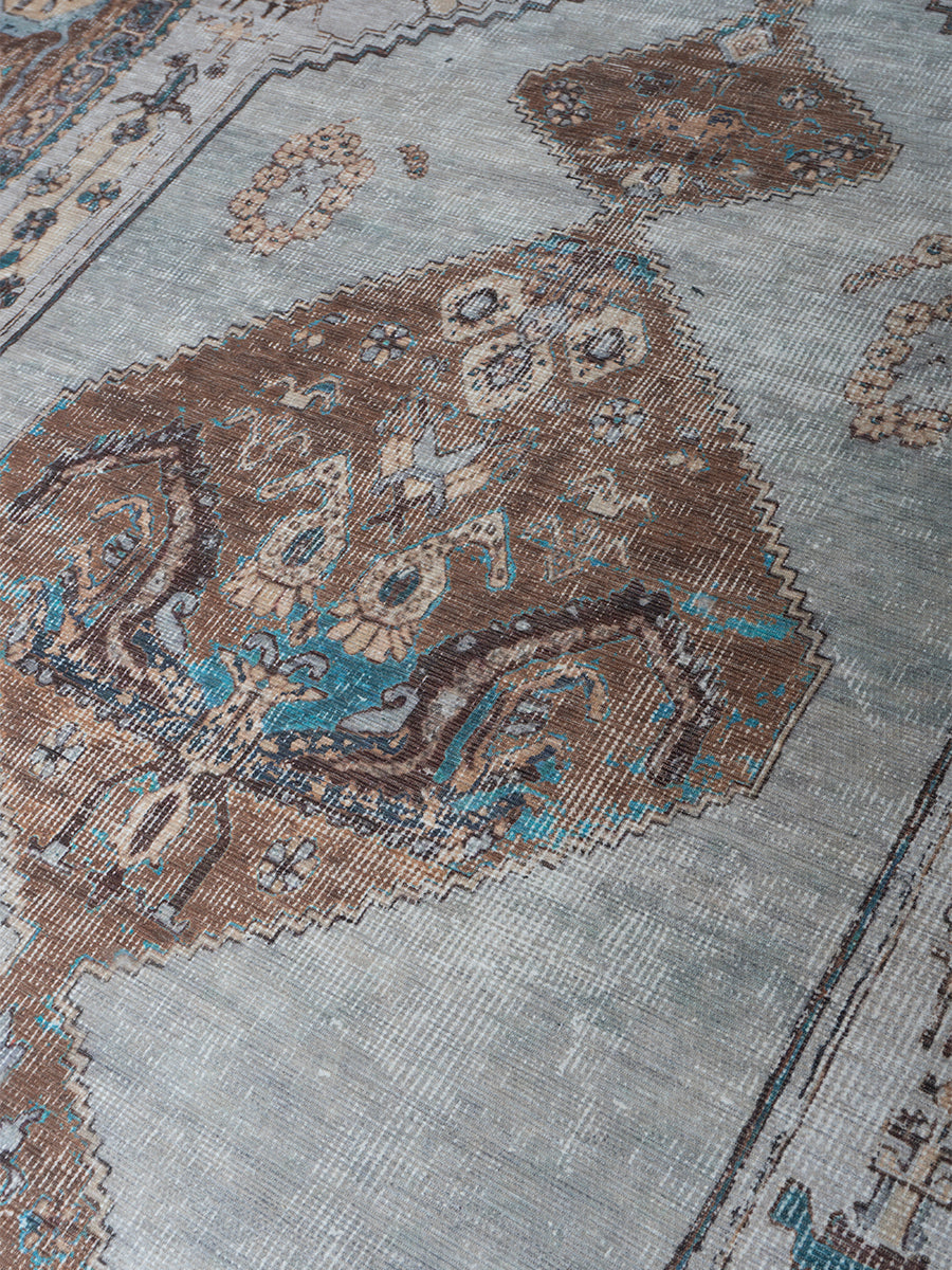 Vloerkleed close-up met grijsblauwe basis en bruinblauwe medaillons en randen