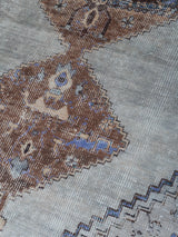 Vloerkleed close-up met lichtgrijs, bruin en blauw geometrisch motief en weefstructuur