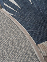 Vloerkleedrand met beige bies en blauwgrijze palmenprint, close-up.