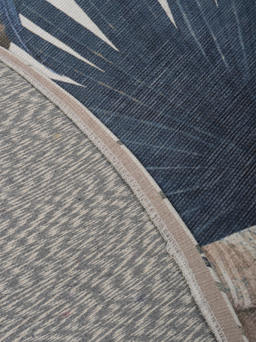Rond vloerkleed detail: beige randafwerking en blauwgrijze pool met bladerenprint.