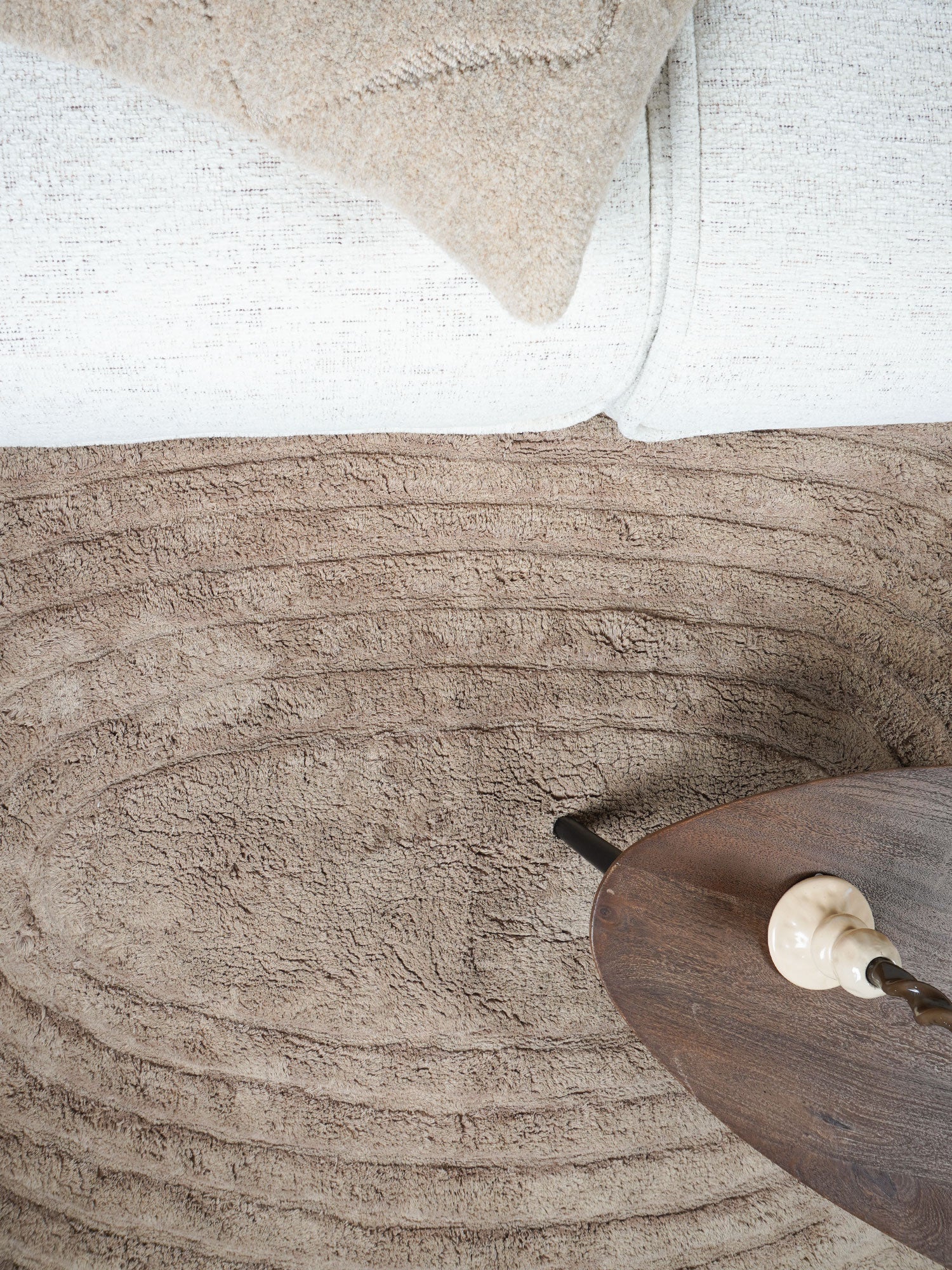 Taupe vloerkleed met ingedrukt, golvend reliëf en geribde banen; close-up